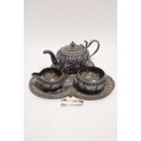 An Indian three-piece tea service of squat round form with repoussé floral decoration highlighted in