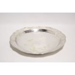 A LARGE CIRCULAR SHALLOW DISH with shaped rim to the raised border, with engraved monogram & die-