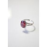 A RUBY & DIAMOND RING, the oval-cut ruby measuring approx. 13mm x 10mm, set within a border of small