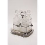 A rectangular decanter frame with centre ring handle, fitted four cut glass decanters with