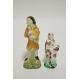A Whieldon-type creamware standing figure of a girl holding a basket of flowers, decorated with