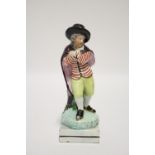 An early 19th century Staffordshire pearlware standing male figure of a skater wearing cloak &
