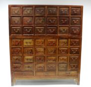 A Chinse hardwood tall chest in two sections, fitted forty five small drawers with brass handles, on