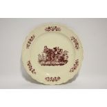 An 18th century creamware plate with moulded scroll border, & red transfer scene of Harlequin &