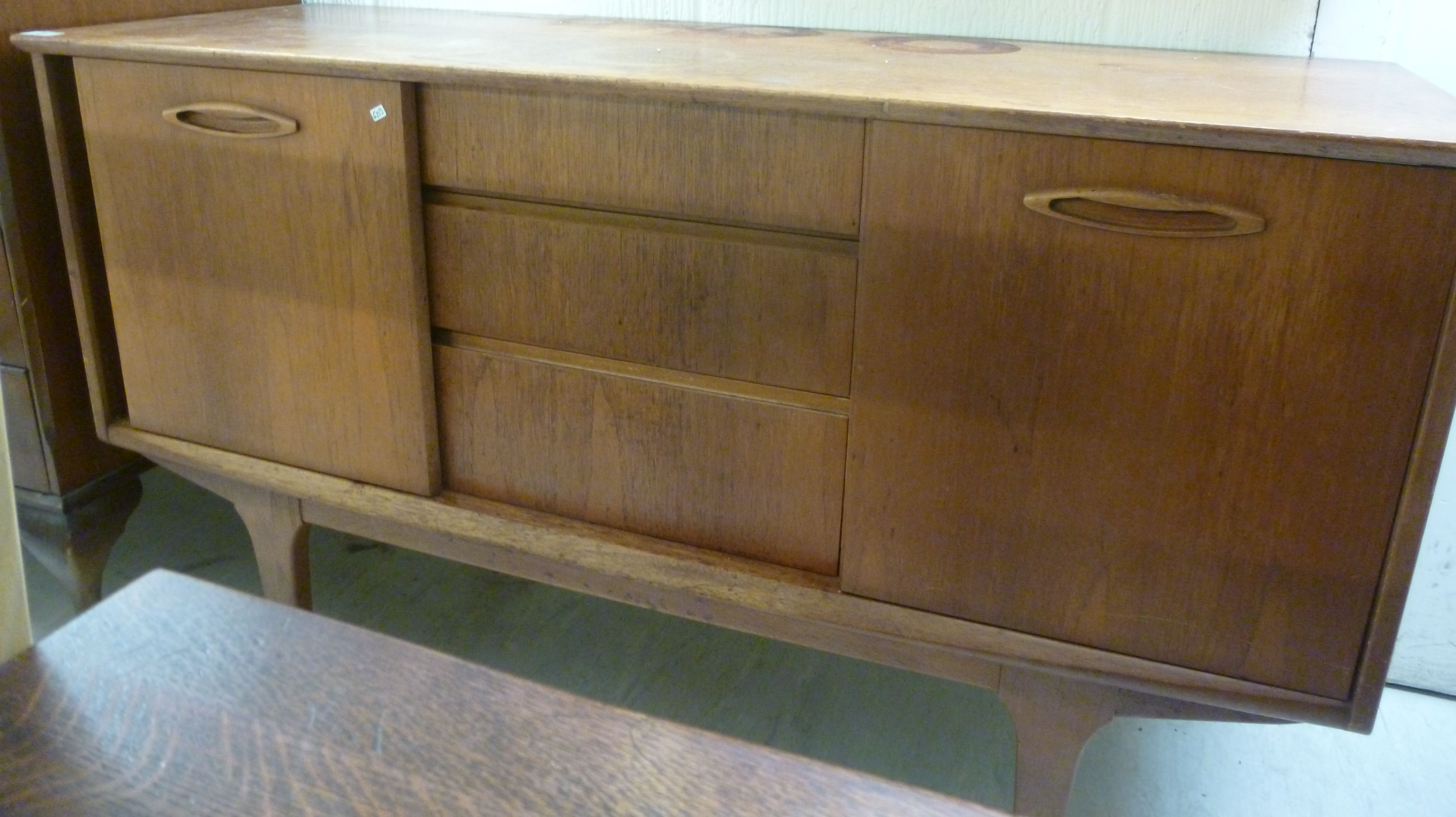 A 1970s teak sideboard, having three cen