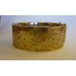 A 9ct gold hinged, wide bangle, on a saf
