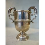 A silver trophy cup with a moulded waist