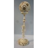 An early 20thC Japanese finely carved ivory puzzle ball, set in a cup,