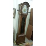 A modern walnut longcase clock, the arched hood over a bevelled glazed panelled pendulum door,