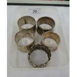 Five dissimilar silver napkin rings: to include one with pressed foliate ornament Birmingham 1922