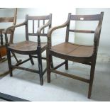 Two early 19thC mahogany and elm open arm chairs, one having a splat back, the other a bar back,