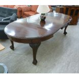 A 1920s mahogany wind-out dining table, the oval top with a carved edge,