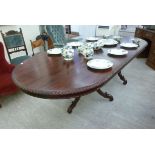 A modern mahogany finished twin pedestal dining table, having an oval top with a carved edge,