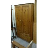 A Ducal pine wardrobe with a pair of panelled doors over a long drawer, raised on turned,