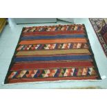 A Kelim rug with stripes and geometric motifs on a red,