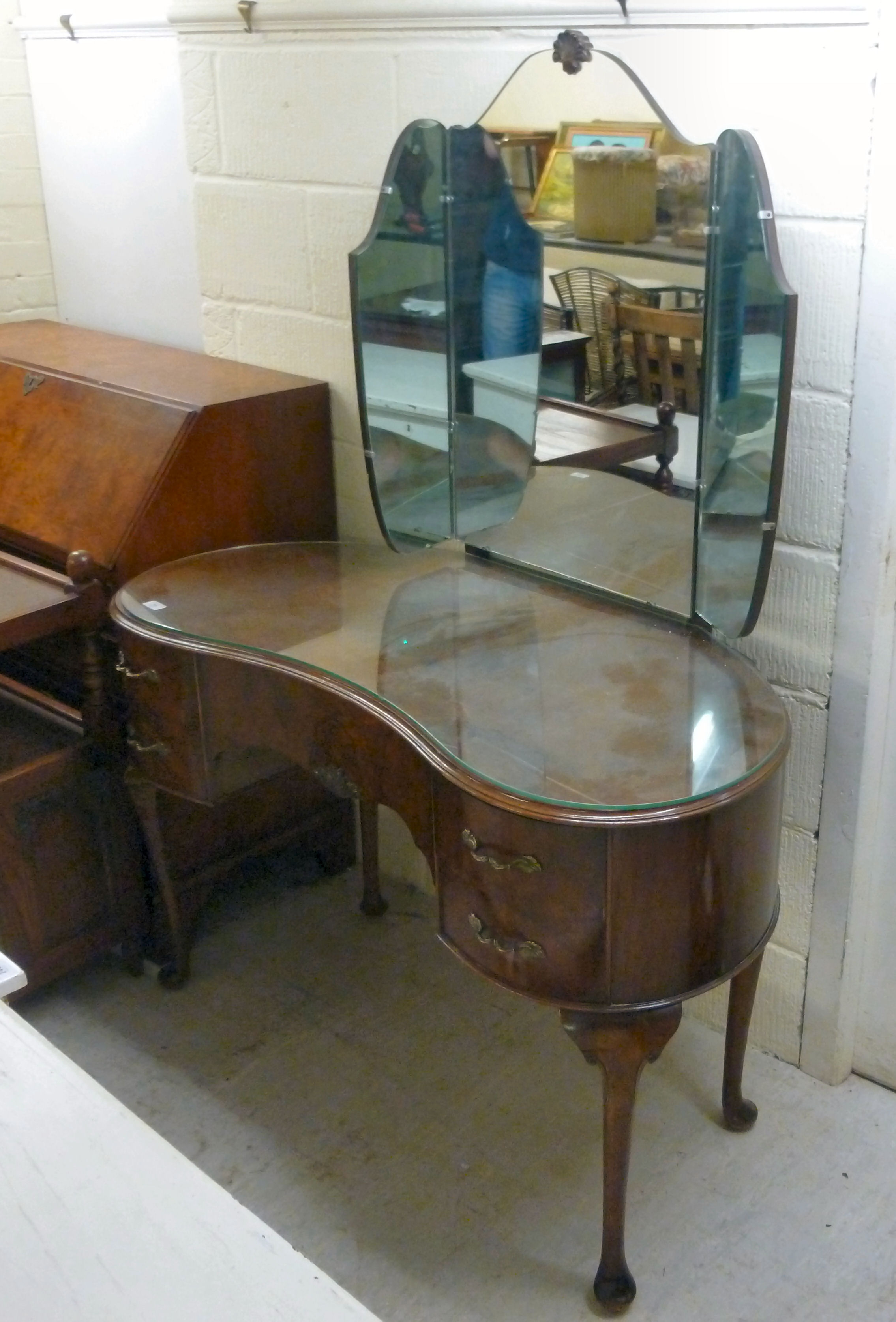 A mid 20thC walnut kidney shaped dressing table, surmounted by a mirror, over five drawers,