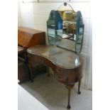 A mid 20thC walnut kidney shaped dressing table, surmounted by a mirror, over five drawers,