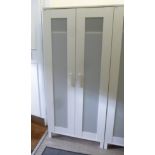 A modern Ikea white painted wardrobe with a pair of frosted plastic panelled doors,