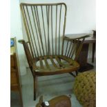 An Ercol stained beech and elm framed spindle back open arm chair, the webbed seat,