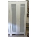 A modern Ikea white painted wardrobe with a pair of frosted plastic panelled doors,