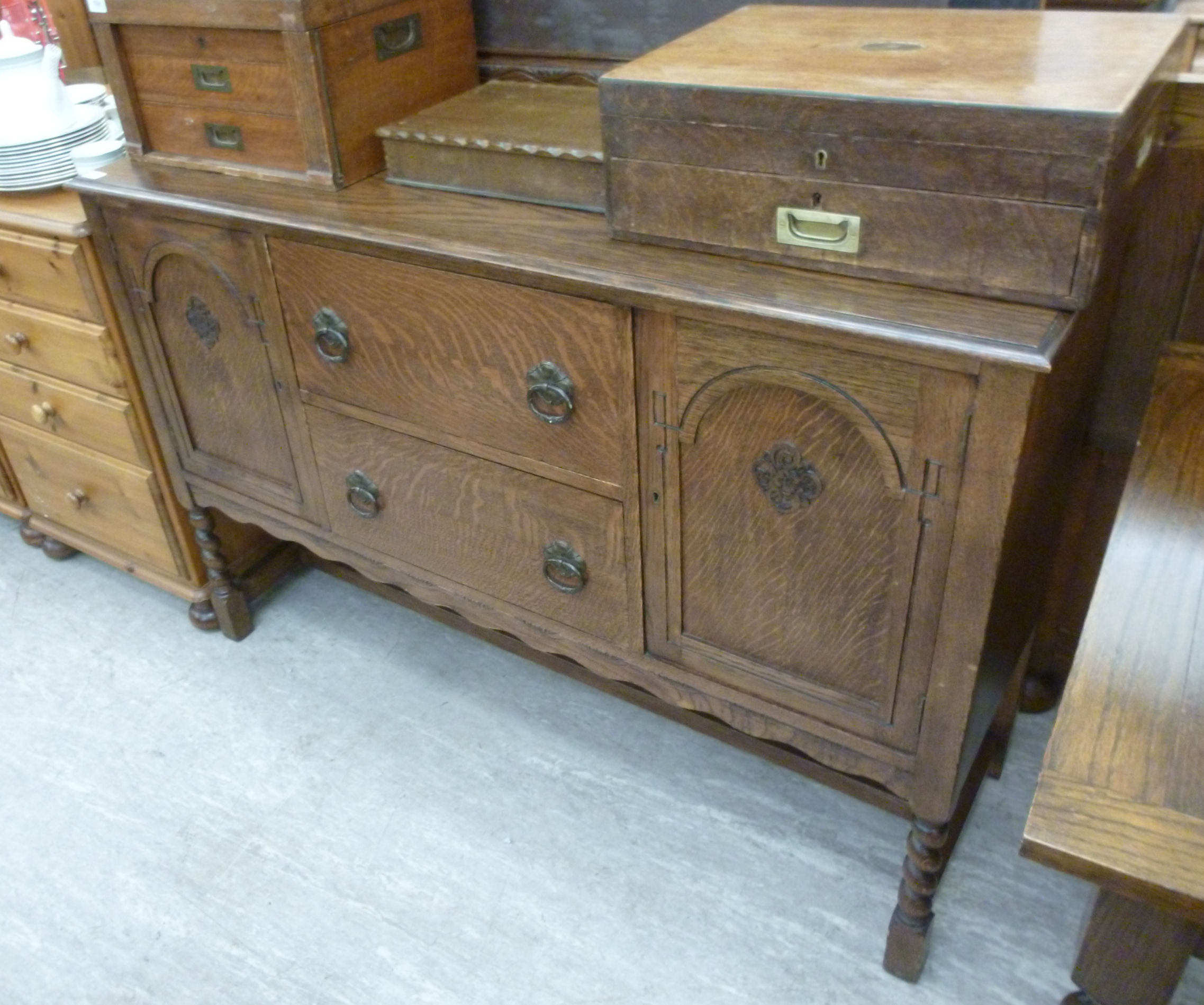 A 1930s oak sideboard with two drawers, flanked by a pair of doors, raised on barleytwist,