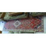 A Persian runner with a medallion and geometric flowers on a red ground 40'' x 118'' BSR