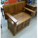 A 1930s oak monks bench with a rising top, box base and a hinged seat,