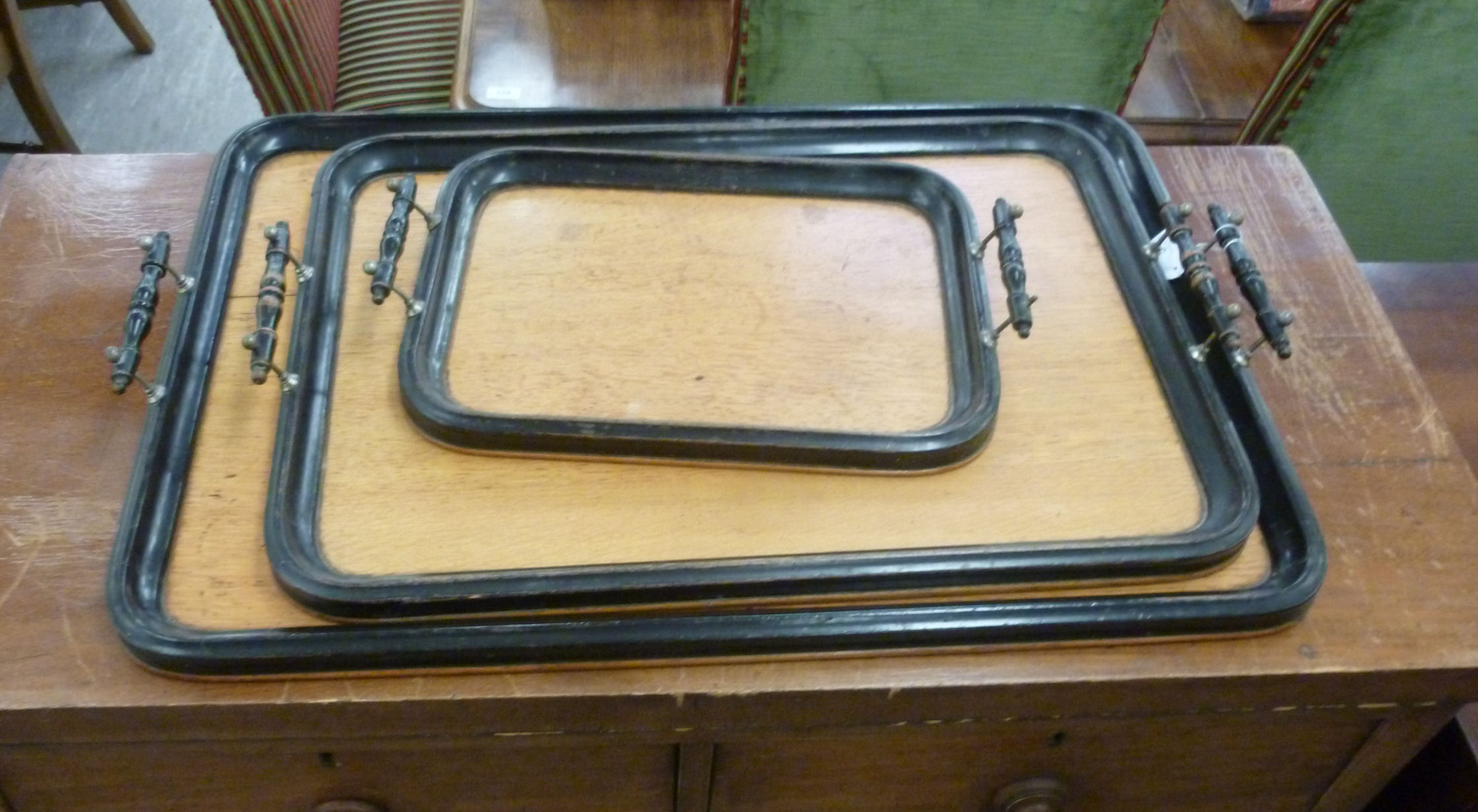 A graduated set of three mid 20thC ebonised and light oak serving trays largest 26'' x 16''