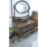 A 1920s stained oak dressing table with a pivoting oval mirror,