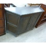 A modern JC stained oak sideboard with canted sides and a pair of carved doors,