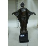 A cast and patinated bronze nude figure, a woman with her arms outstretched,