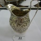 A George III silver milk jug with ornate embossed decoration London mark indistinct 11