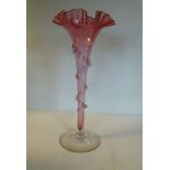 A late Victorian Cranberry glass vase of trumpet design with a frilled wavy lip,