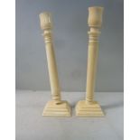 A pair of early 20thC ivory candlesticks, each having a flared socket,