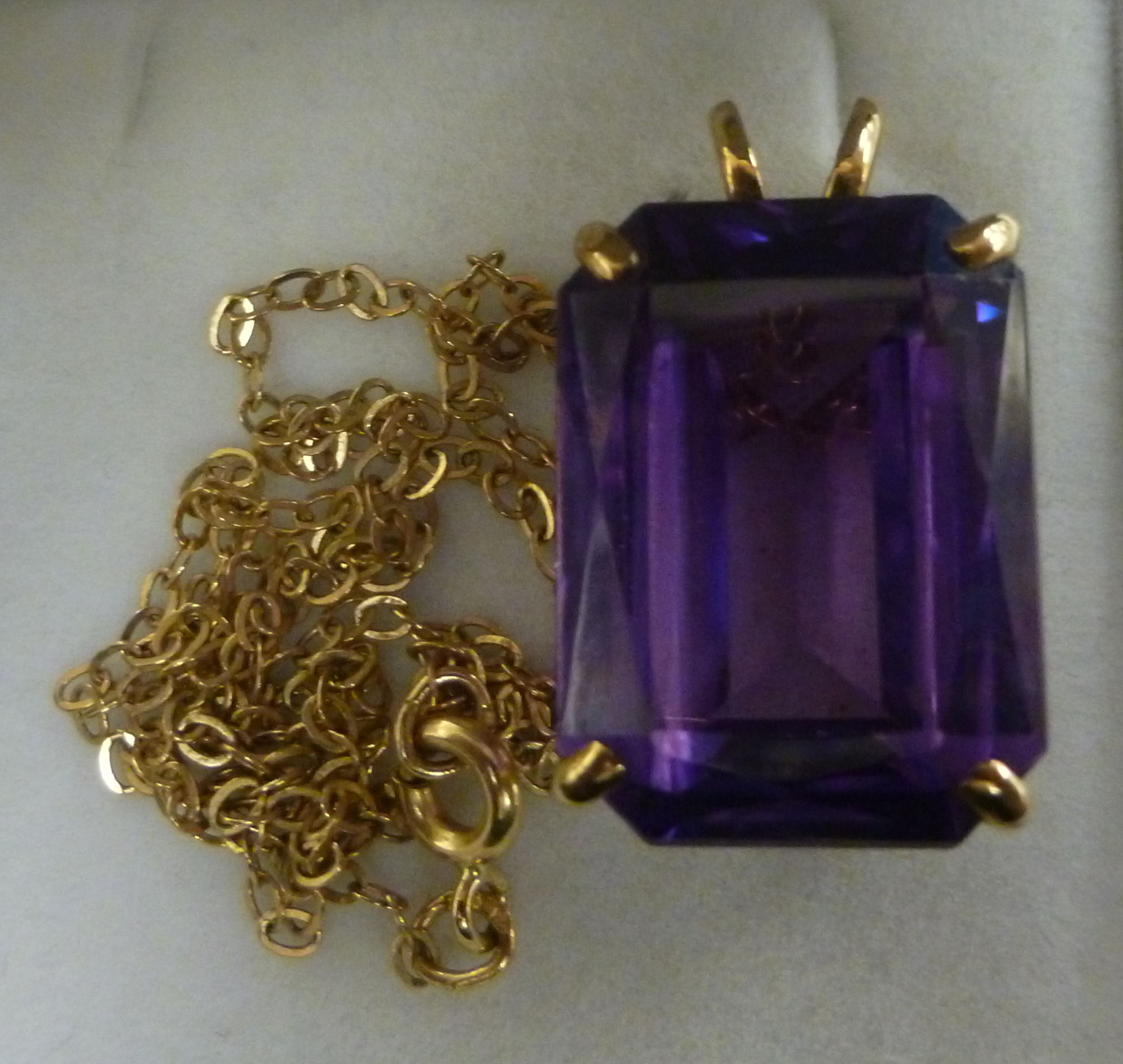 A 9ct gold pendant, set with an amethyst coloured stone,