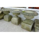 A set of three composition stone demi-reeded vase design terrace urns,