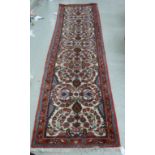 A Persian runner with floral palmets on a red and beige ground 32'' x 110'' BSR