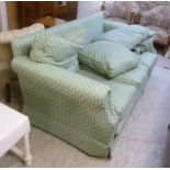 A modern three seater settee with a level back, upholstered in a floral, pale green fabric,