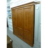 A modern cherrywood finished wardrobe with a moulded cornice, over three doors,