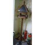 An as new treated pine and slatted bird table with a pitched roof and square column,