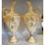 A pair of Royal Worcester gilded blush ivory glazed and moulded china ewers of ovoid form,