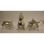 A three piece silver condiments set comprising an ogee shaped salt cellar on pad feet,
