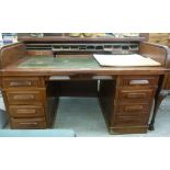 An early 20thC mahogany rolltop desk, having a rising tambour cover, enclosing a green hide scriber,