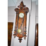 An early 20th Century walnut Vienna wall clock, white enamel roman dial within glazed panel case,