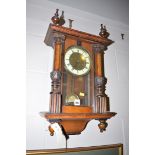 An early 20th Century wall clock, the roman dial within glazed stained wood case,
