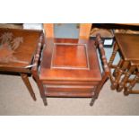 A 19th Century style stained wood commode, turned arms above hinged seat, raised on turned legs.