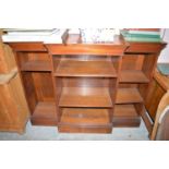 An early 20th Century mahogany breakfront bookcase, the flared cornice above adjustable shelves,