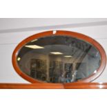 A stained oak framed bevelled oval wall mirror.