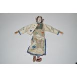 A late 19th/early 20th Century Chinese doll, with carved hand-painted wooden head, silk work robe,