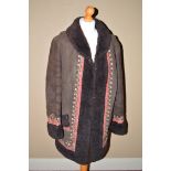 A 1960's half-length sheepskin coat with red and floral decoration to borders,